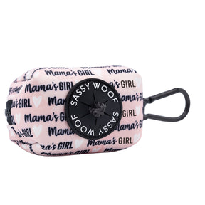 The Sassy Woof Dog Waste Bag Holder - Mama's Girl is a light pink neoprene accessory with black and white Mama's Girl and heart designs, a black circular logo, and a matching black clip for easy attachment.