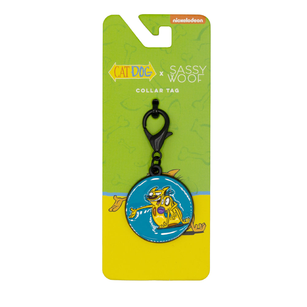 The Sassy Woof Dog Collar Tag - Nickelodeon CatDog™ features a blue circular charm with CatDog artwork, a black clasp, and comes in green and yellow branded packaging—perfect for any CatDog fan's collection.