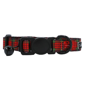 The Sassy Woof Cat Collar - Deck the Paws features a festive red and green plaid pattern, black buckle, round black tag, small silver bell, and a metal loop for leash or tag attachment.