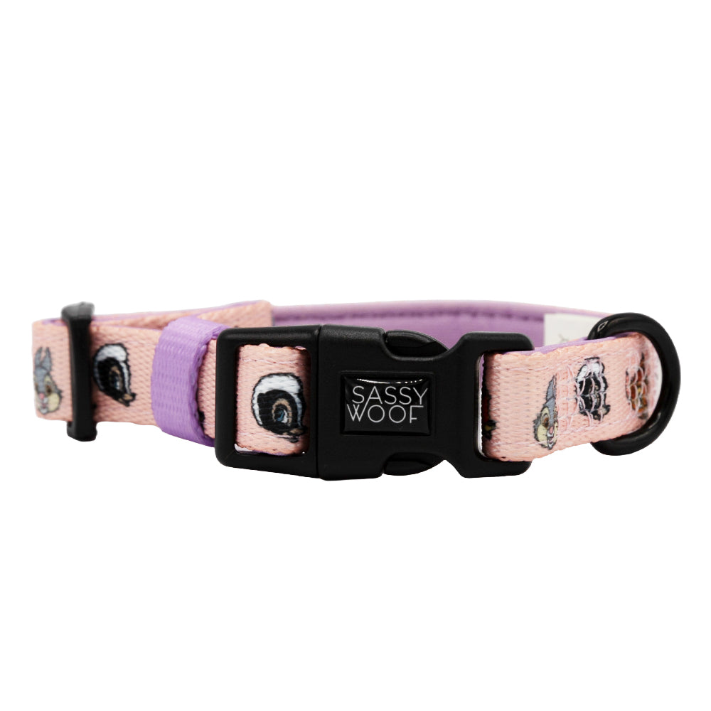 The Sassy Woof Dog Collar – Disney’s Bambi features pink and purple colors, cartoon dog faces, a black plastic buckle labeled "Sassy Woof," neoprene comfort, and a black D-ring for leash attachment.