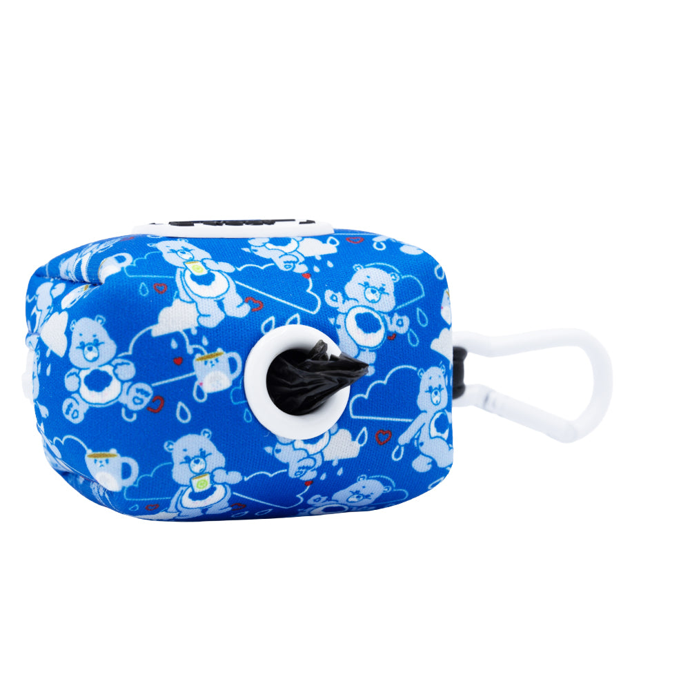 Carry the Sassy Woof Dog Waste Bag Holder - Care Bears™ Grumpy Bear—a blue pouch with cheerful bear design, white plastic clip, and black bag dispenser—for a stylish walk that matches your Care Bears dog harness.
