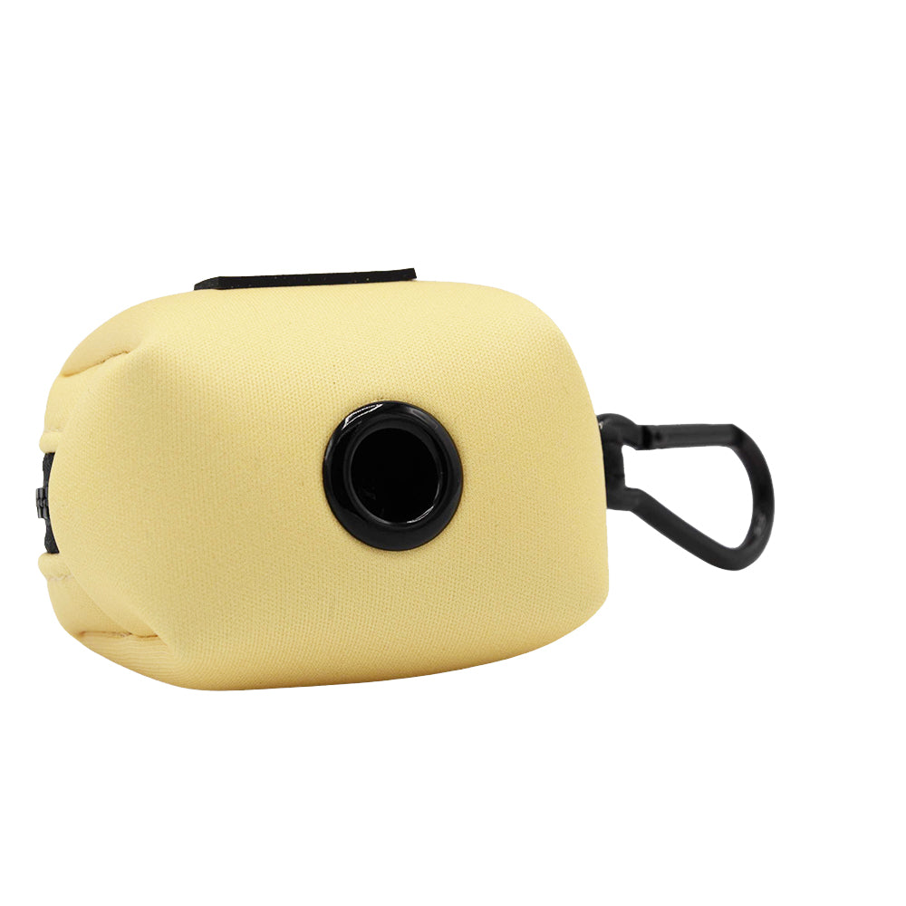 The Sassy Woof Dog Waste Bag Holder - Daffodil is a soft, light yellow neoprene holder with a black circular opening and plastic clip—perfect for dispensing dog bags on walks.
