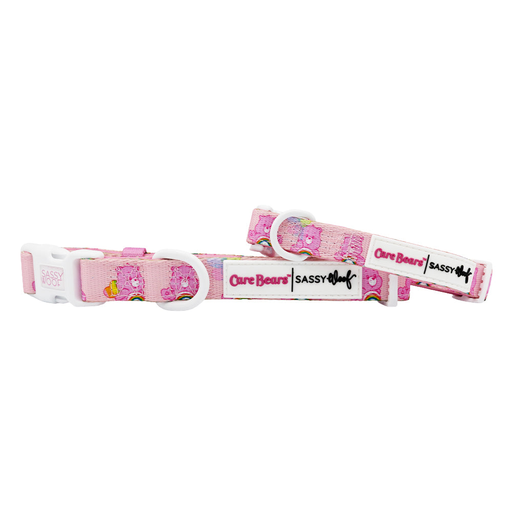 The Sassy Woof Dog Collar - Care Bears™ Cheer Bear features pink Care Bears designs, white plastic clips, and branded tags. Pair it with a matching harness for a complete Care Bears look.