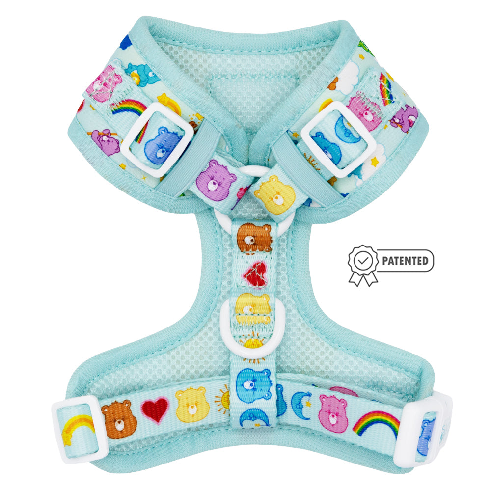 The Sassy Woof Dog Adjustable Harness - Care Bears™ Care-a-Lot features a light blue design with colorful Care Bears faces, rainbows, hearts, and stars. It has white buckles, a PATENTED badge, and includes the Puppy Growth Pawtection Plan.