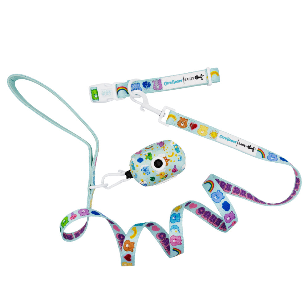 The Sassy Woof Collar Three Piece Bundle - Care Bears™ Care-a-Lot features a vibrant collar, leash, and waste bag holder with nostalgic bear faces, hearts, and rainbows on white—perfect for stylish pet lovers.