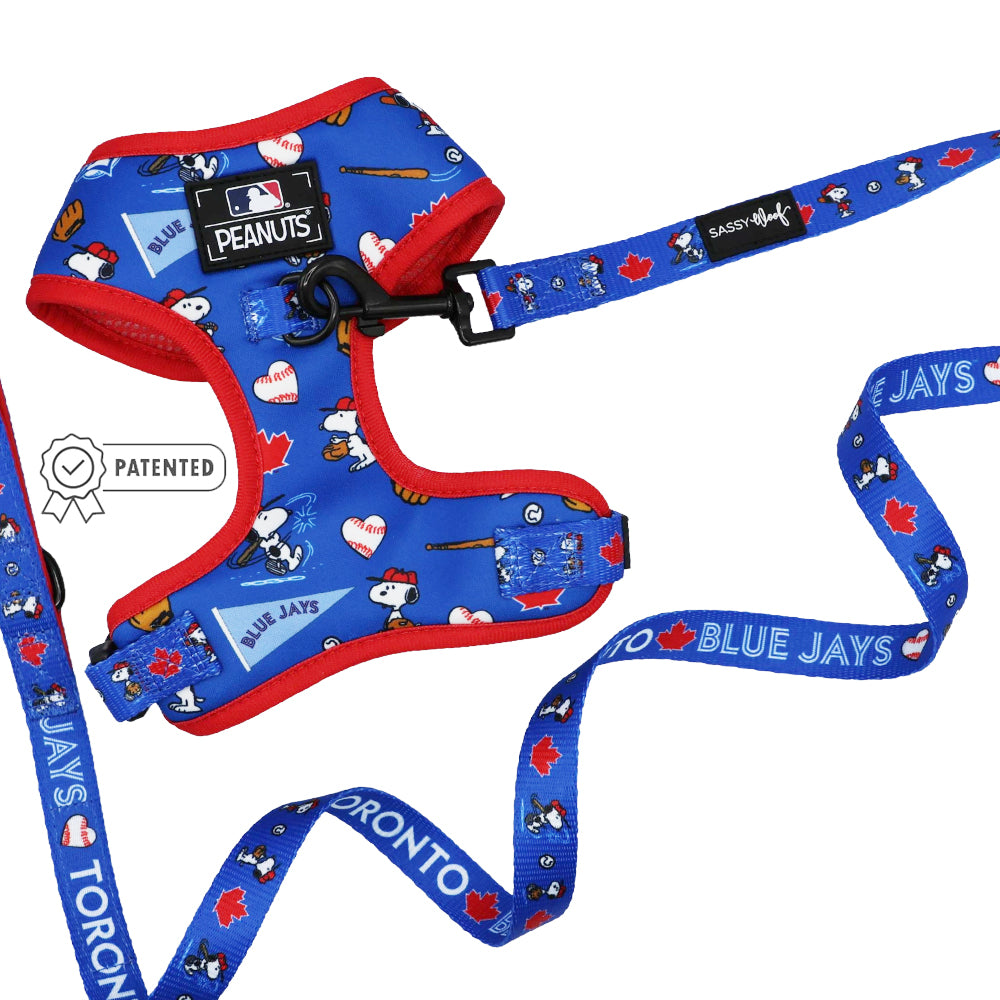 The Sassy Woof Dog Two Piece Bundle - MLB™ x Peanuts™ Toronto Blue Jays™ features a blue and red Snoopy harness and leash with baseball bats, hearts, team logos, "Toronto Blue Jays" text, maple leaves, and a Patented badge.