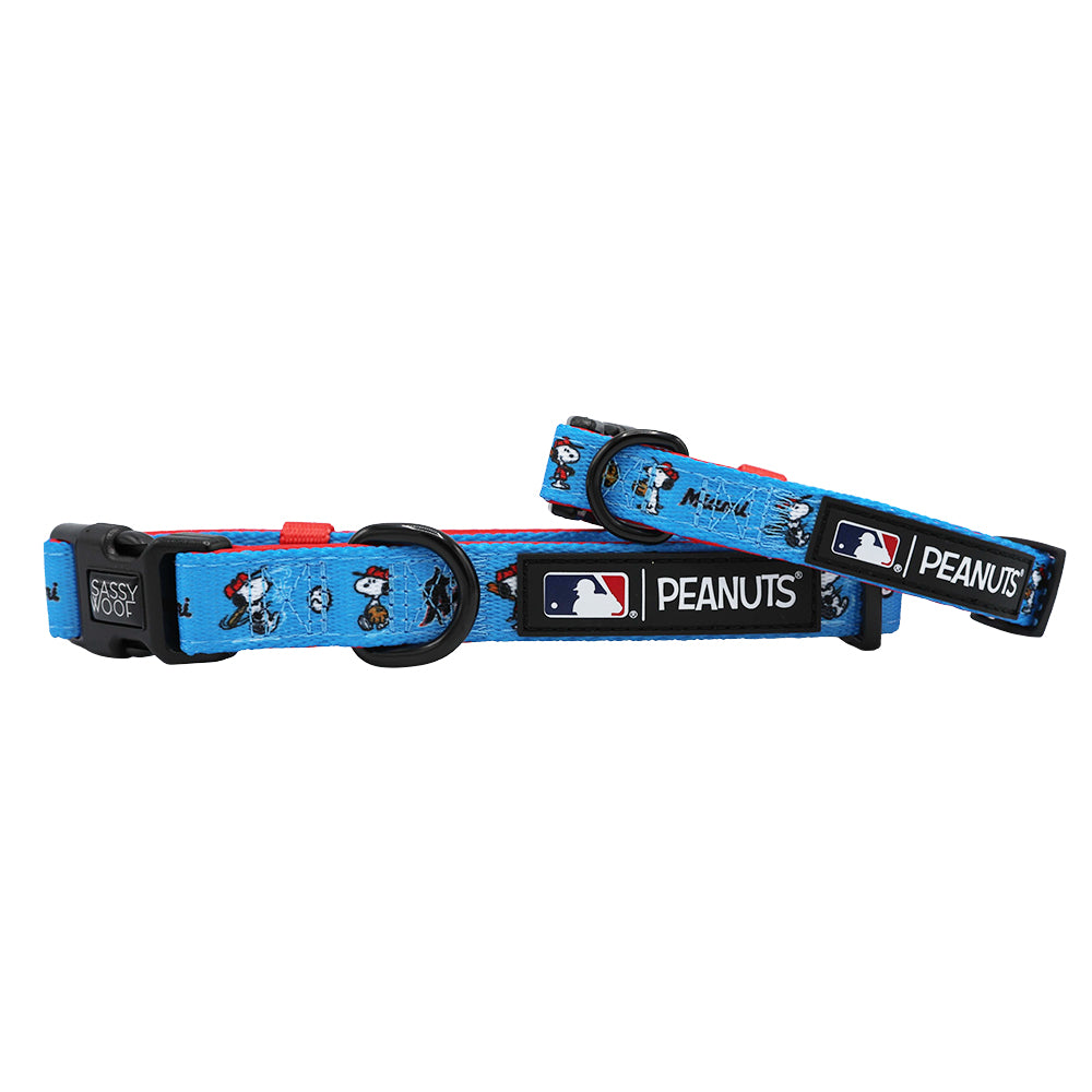 Two blue adjustable Sassy Woof dog collars from the MLB™ x Peanuts™ Miami Marlins™ collection, with red trim, Snoopy and Woodstock designs, MLB and Peanuts logos on black patches, plastic buckles, and metal D-rings.