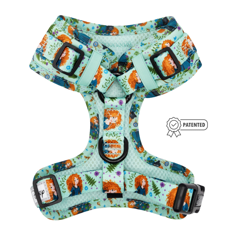 The Sassy Woof Dog Adjustable Harness - Disney's Merida features a teal design with black buckles, cartoon characters, orange-haired girls, floral patterns, and a patented icon displayed to the right of the harness.
