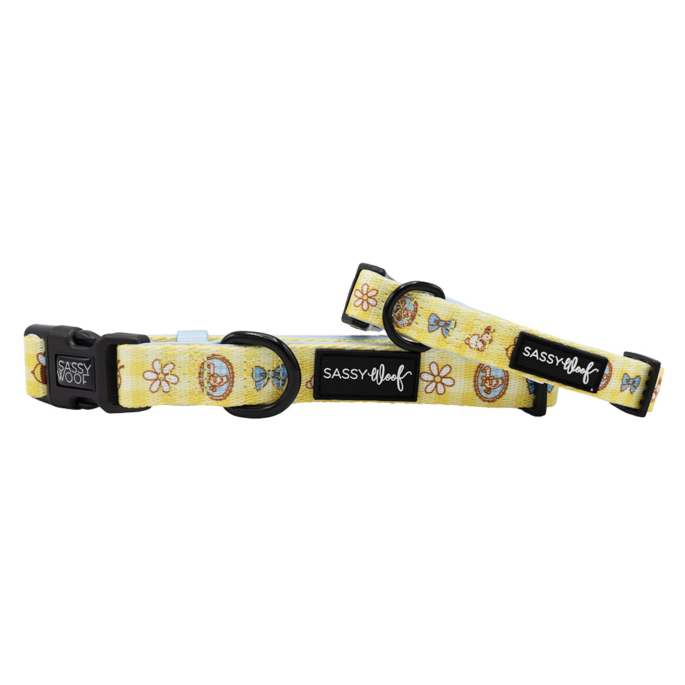 Two yellow Sassy Woof Patch Perfect dog collars with cartoon donuts, bows, and white flowers. Made from soft neoprene with black plastic buckles and sliders—adjustable for puppy growth.