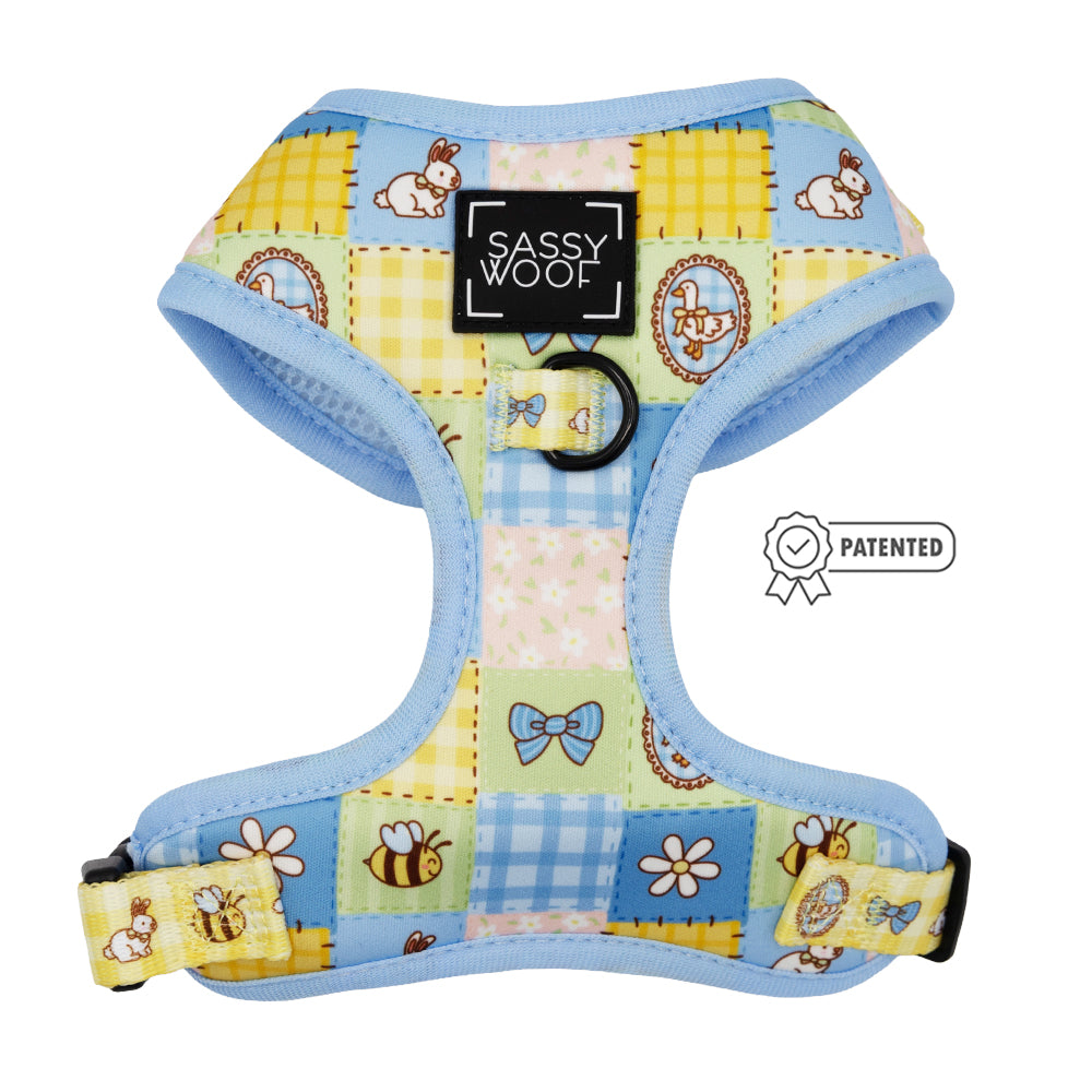 The Sassy Woof Dog Two Piece Bundle - Patch Perfect is a pastel blue adjustable harness with bunnies, bows, flowers, and bees. It features a black Sassy Woof label, metal ring at the front, and a patented badge on the right side.