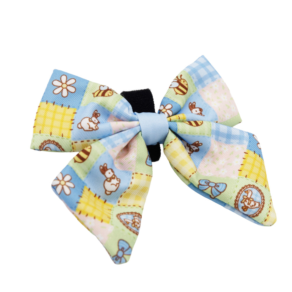 The Sassy Woof Dog Sailor Bow - Patch Perfect features a quilted pastel design with bunnies, flowers, and geometric shapes in blue, yellow, and green tones.