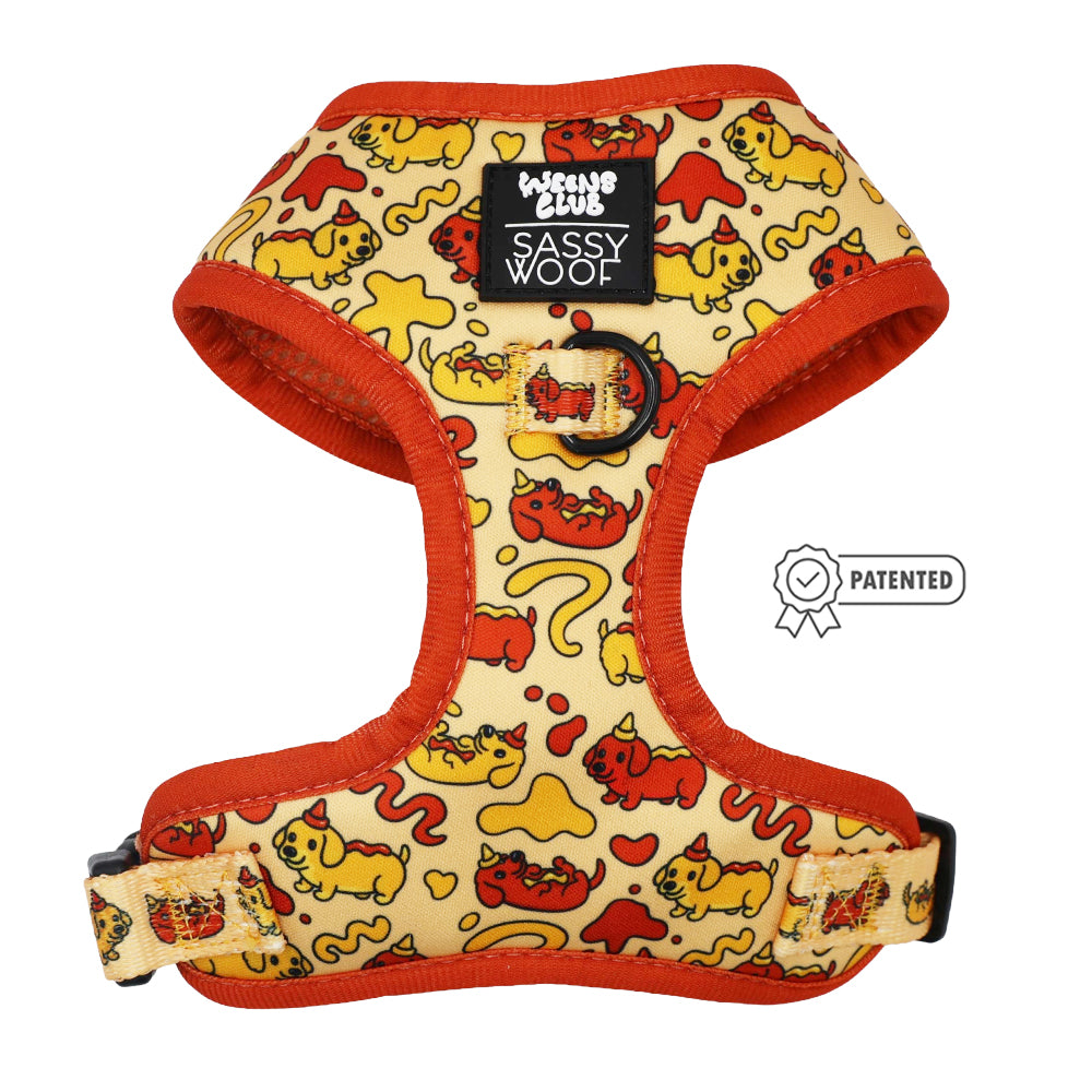The Sassy Woof Dog Four Piece Bundle - Hot Dawg features a red and yellow cartoon dachshund print, orange trim, adjustable straps, and a Sassy Woof label with a small Patented badge icon to the right.