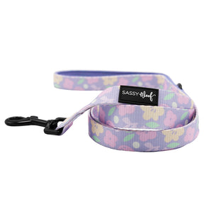 The Dog Leash - Fleur de Sass by Sassy Woof features a pastel purple floral design, comfy neoprene handle with Sassy Woof label, and a black clip—ideal to pair with your favorite adjustable dog harness.