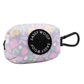 The Sassy Woof Dog Waste Bag Holder - Fleur de Sass features a pastel floral neoprene design, black clip, and round black Sassy Woof label—perfect for pairing with your Fleur de Sass adjustable harness.