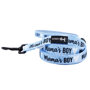 The Sassy Woof Dog Leash - Mama's Boy is light blue with black hardware, "Mamas Boy" and white hearts in black script, plus a small Sassy Woof tag. Pair it with the matching adjustable harness for a coordinated look.