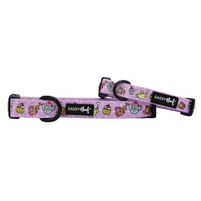 Two "Tea Pawty" dog collars by Sassy Woof in purple with playful cupcake, teapot, and teacup designs. Each neoprene collar has a sturdy D-ring, black plastic buckle, and a black Sassy Woof tag.