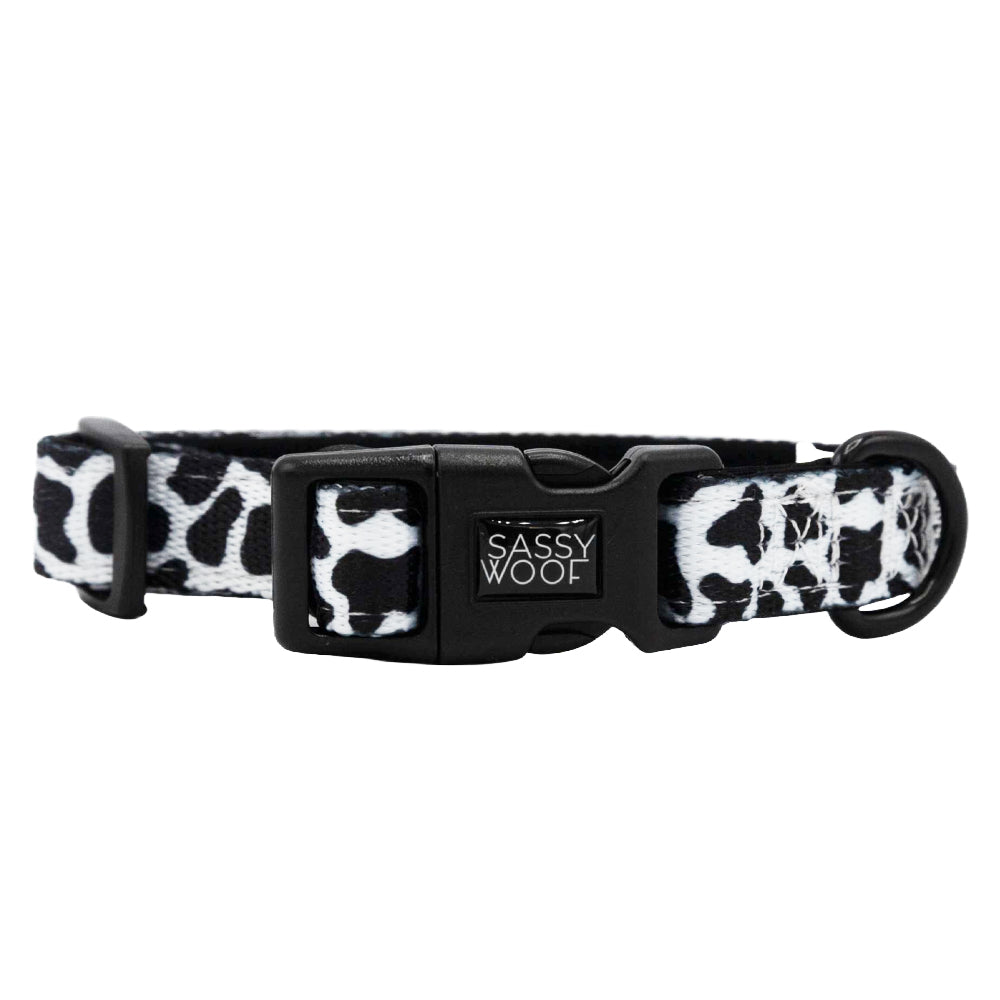 The Dog Collar - Whole Milk by Sassy Woof features a black and white cow print with a black plastic buckle. This adjustable collar is stylish and comfortable for your pup.