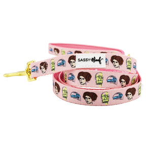 The Sassy Woof Dog Leash - STAR WARS™ Princess Leia features a pink design with cartoon Leia, C3PO, and R2D2, a gold clasp, and the Sassy Woof label.