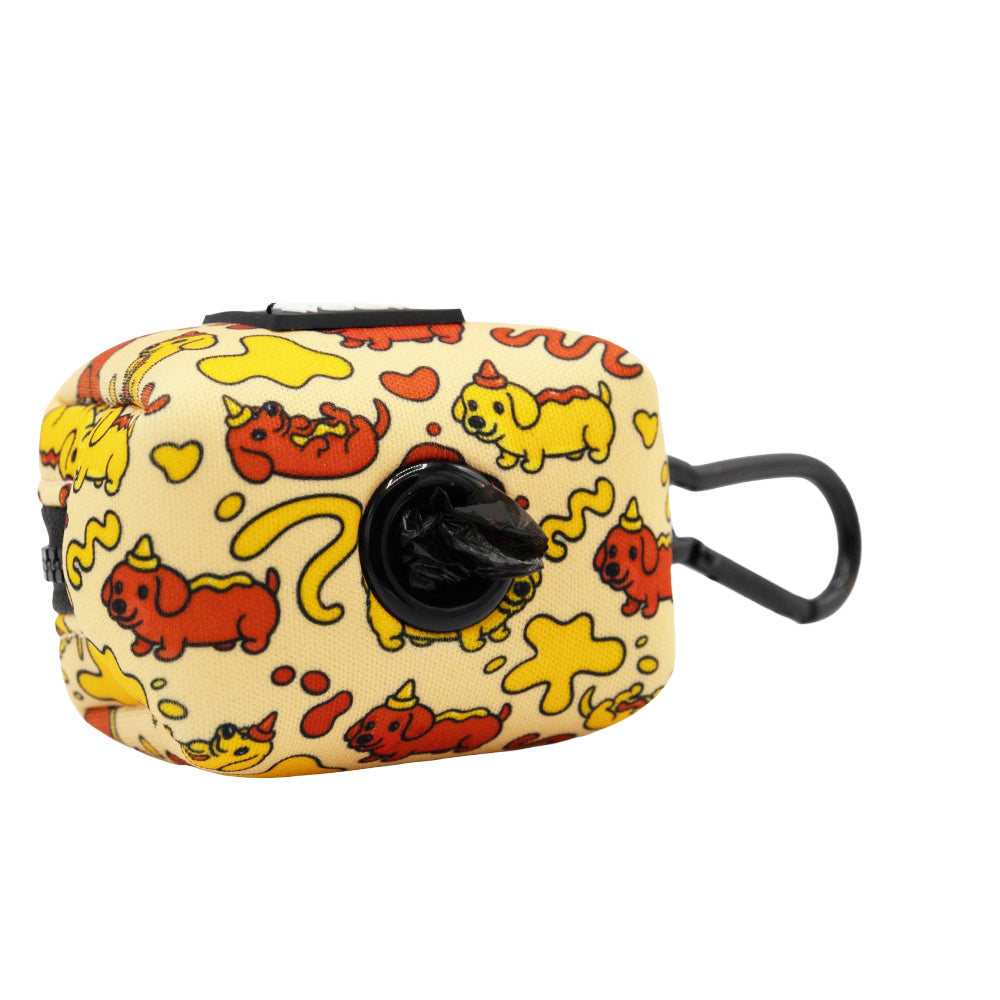 The Sassy Woof Dog Waste Bag Holder - Hot Dawg is a rectangular neoprene dispenser with a clip, featuring red and yellow cartoon dachshunds, stars, and hearts on cream—perfect for your dachshund accessories or weenie dog collection.