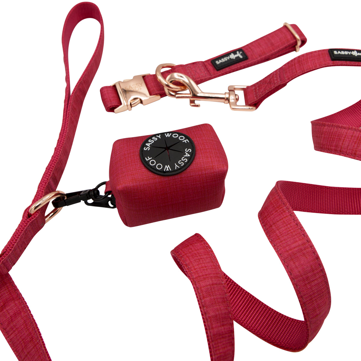 The Sassy Woof Collar Three Piece Bundle - Merlot features a red leash, collar, and waste bag holder with rose gold hardware, all arranged stylishly on a white background.