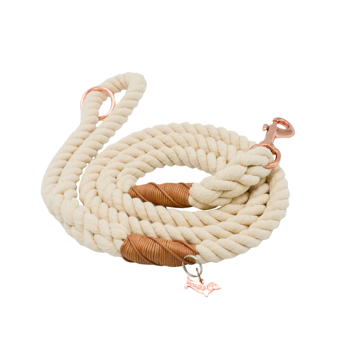 The Sassy Woof Dog Rope Leash - Natural features a coiled, thick, cream cotton rope with brown leather accents, a copper clasp, and a playful dog-shaped charm for added style and durability.