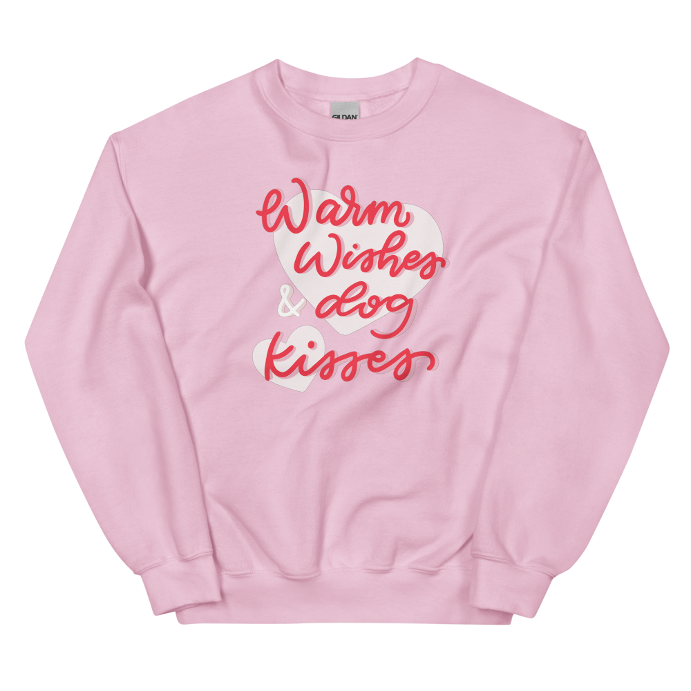 The Sassy Woof "Warm Wishes & Dog Kisses" sweatshirt features soft, light pink fabric with the phrase in playful red and white script across the front.