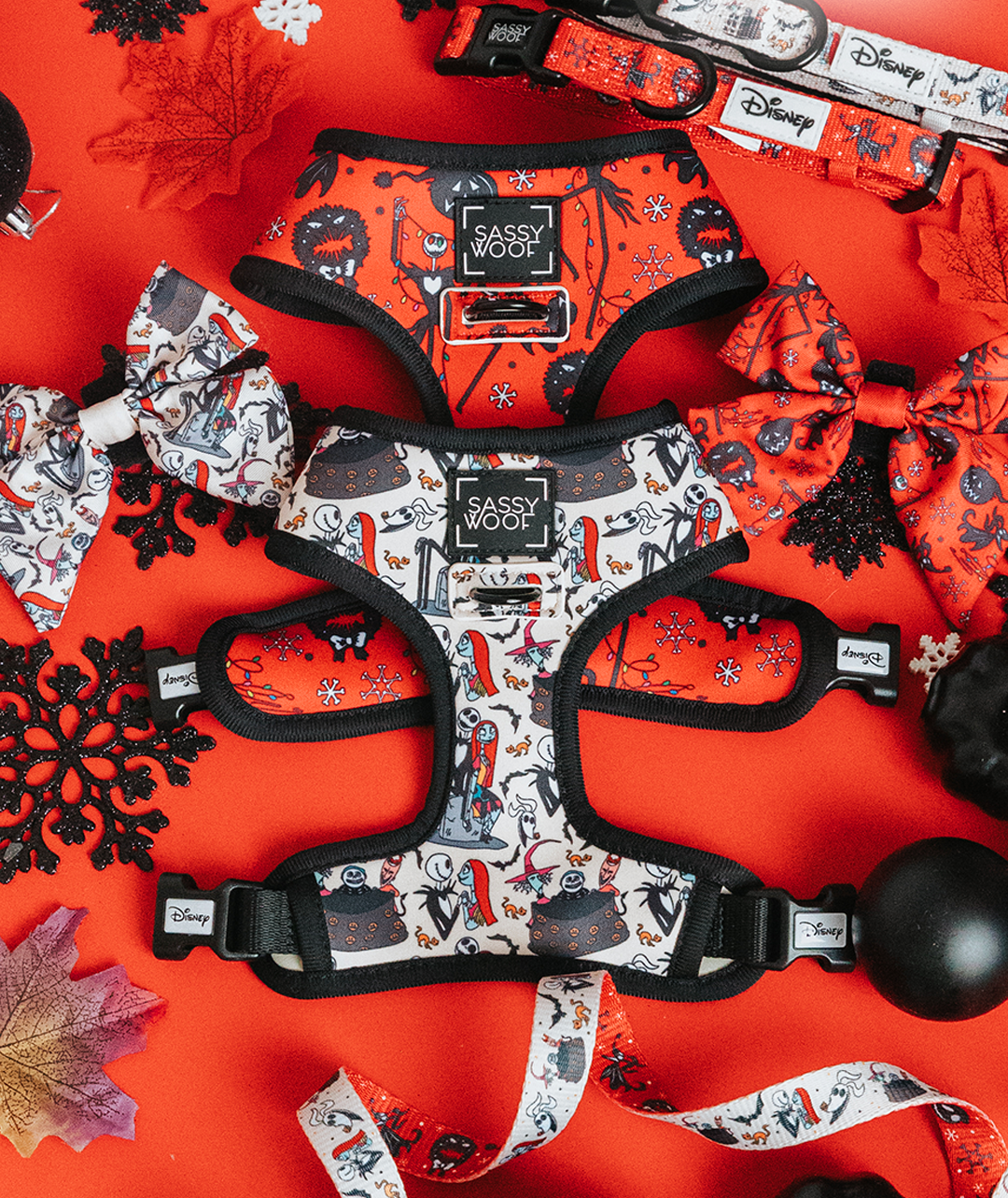 Colorful Disney-themed dog harnesses, collars, and bows with black trim are arranged on a bright red background, surrounded by decorative leaves and snowflake ornaments.