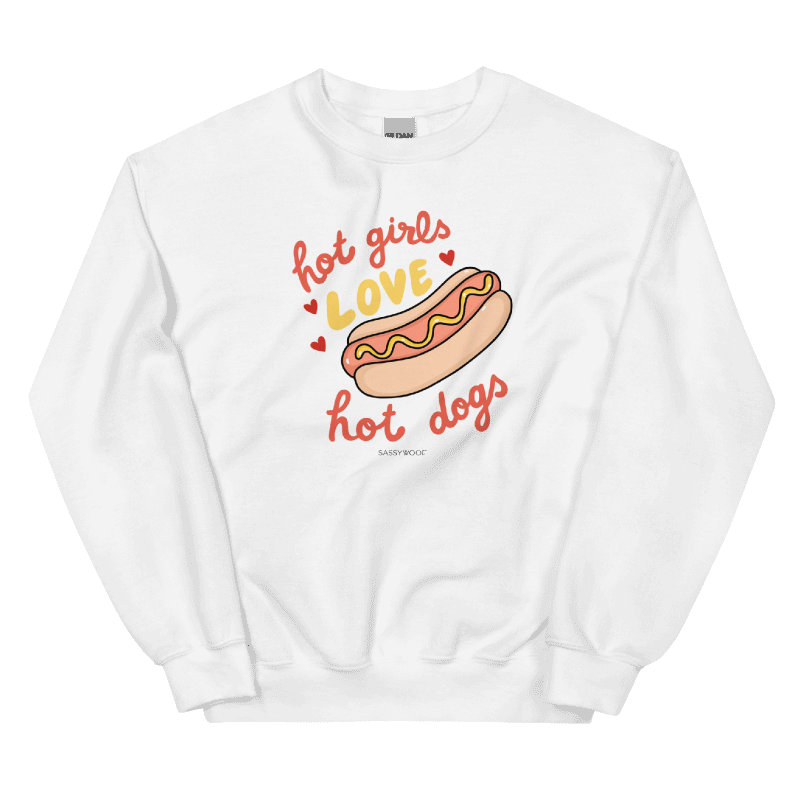 The Sassy Woof Sweatshirt - Hot Girls Love Hot Dogs is a comfy white unisex crewneck featuring a cartoon hot dog, playful red and yellow hearts, and bold "hot girls love hot dogs" text—perfect for loungewear.