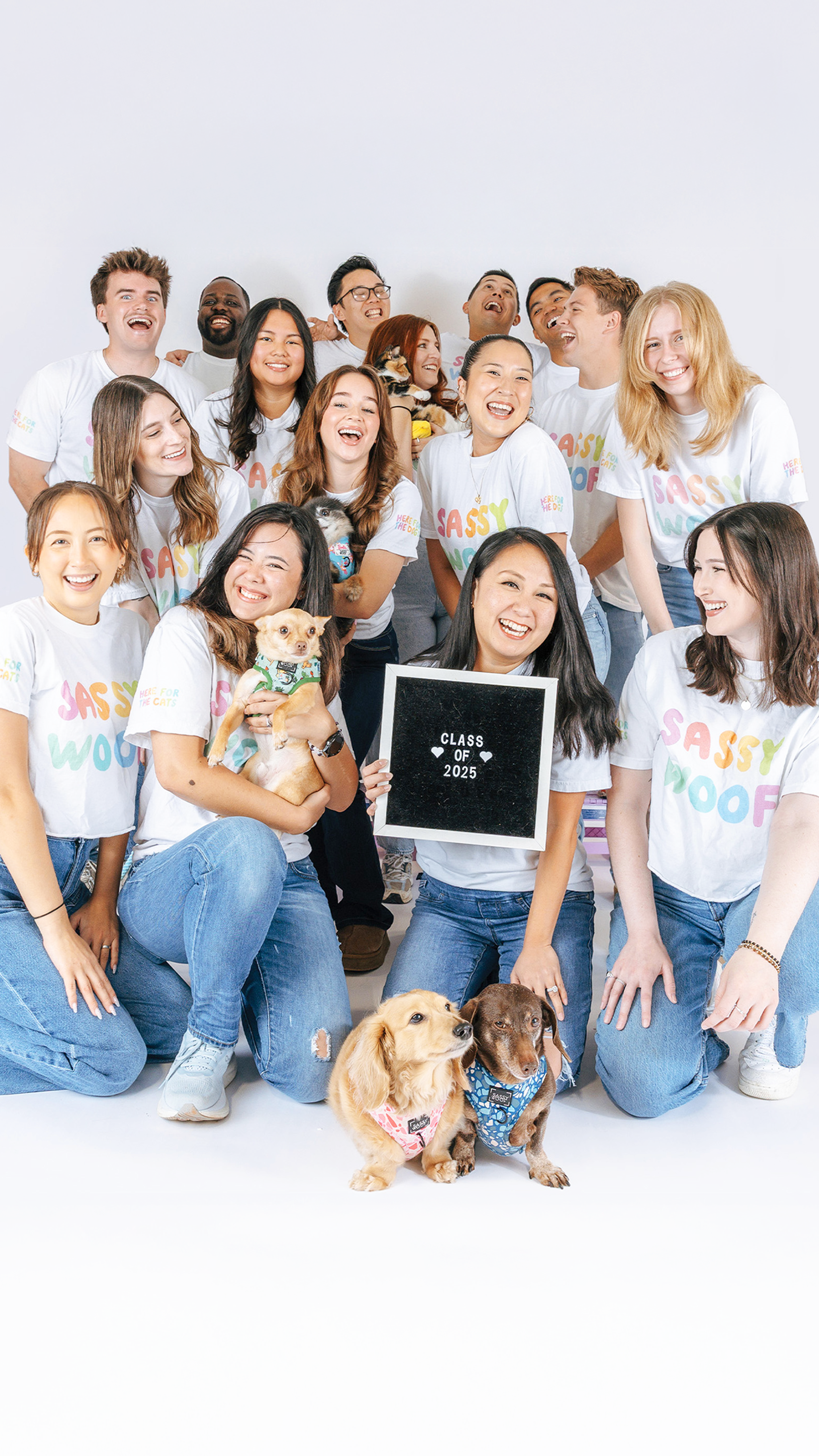 Group of people and dogs posing together with 'Class of 2025' shirts on a white background