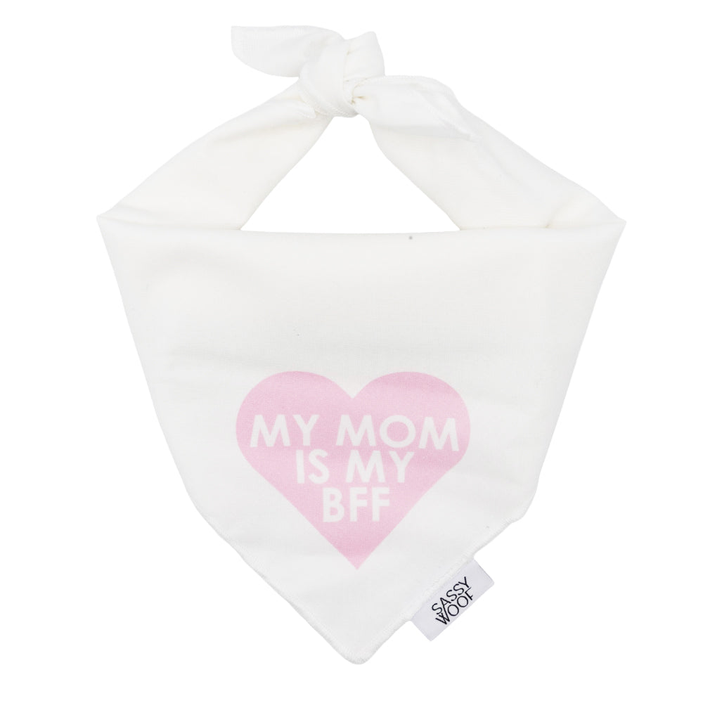 The Sassy Woof Dog Bandana - My Mom is my BFF (PINK) is a lightweight white cotton accessory with a pink heart, cute "MY MOM IS MY BFF" print, top tie closure, and a Sassy Woof tag on the edge.
