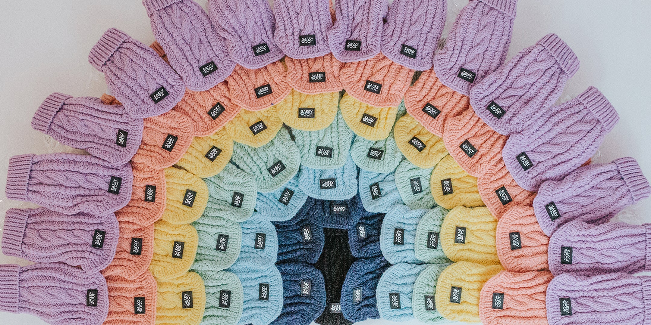 Round rug with a colorful pattern made of knitted gloves arranged in a circular fashion.