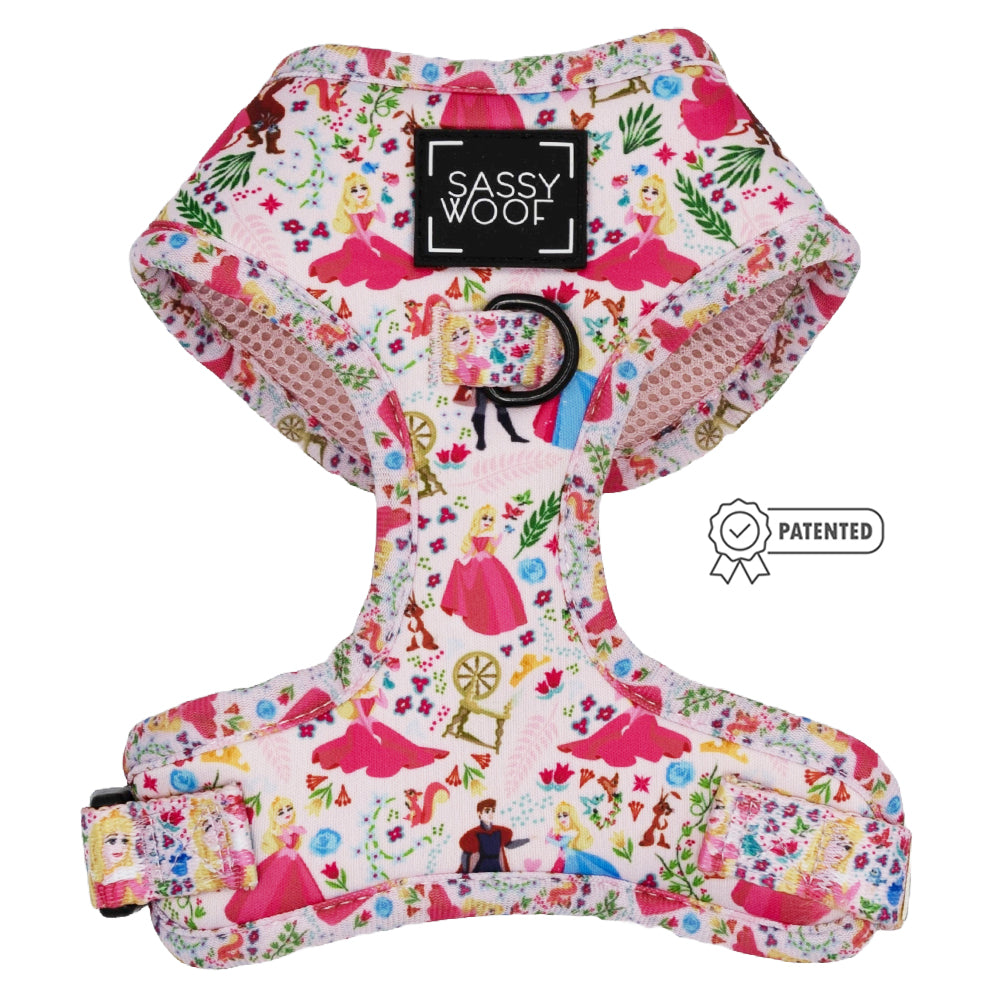 The Sassy Woof Dog Adjustable Harness – Disney's Aurora is a pink and white harness with princess and flower illustrations, a black D-ring, and PATENTED badge. Perfect for your pup’s royal outings!.