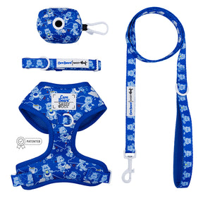 The Sassy Woof Dog Four Piece Bundle - Care Bears™ Grumpy Bear features a blue cartoon-print harness, leash, collar, and waste bag holder with matching designs and a small patent icon near the Grumpy Bear harness.