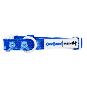 The Sassy Woof Dog Collar - Care Bears™ Grumpy Bear features blue Care Bears graphics, a white buckle and D-ring, plus a logo patch—perfect to pair with your Care Bears dog harness for a coordinated look.