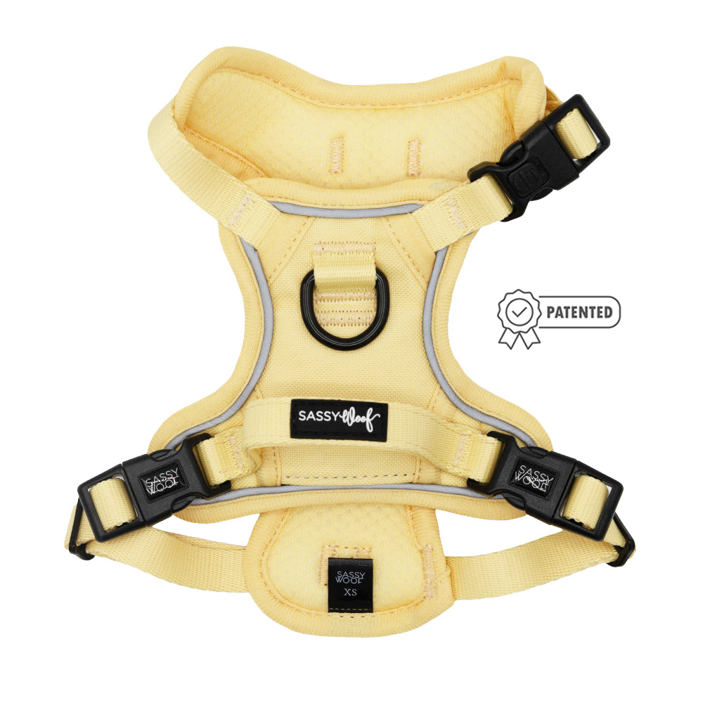 A Sassy Woof Dog Step-in Harness - Daffodil in size XS, featuring a yellow design with reflective trim, black buckles, metal D-ring, AirTag pocket, and PATENTED badge graphic.