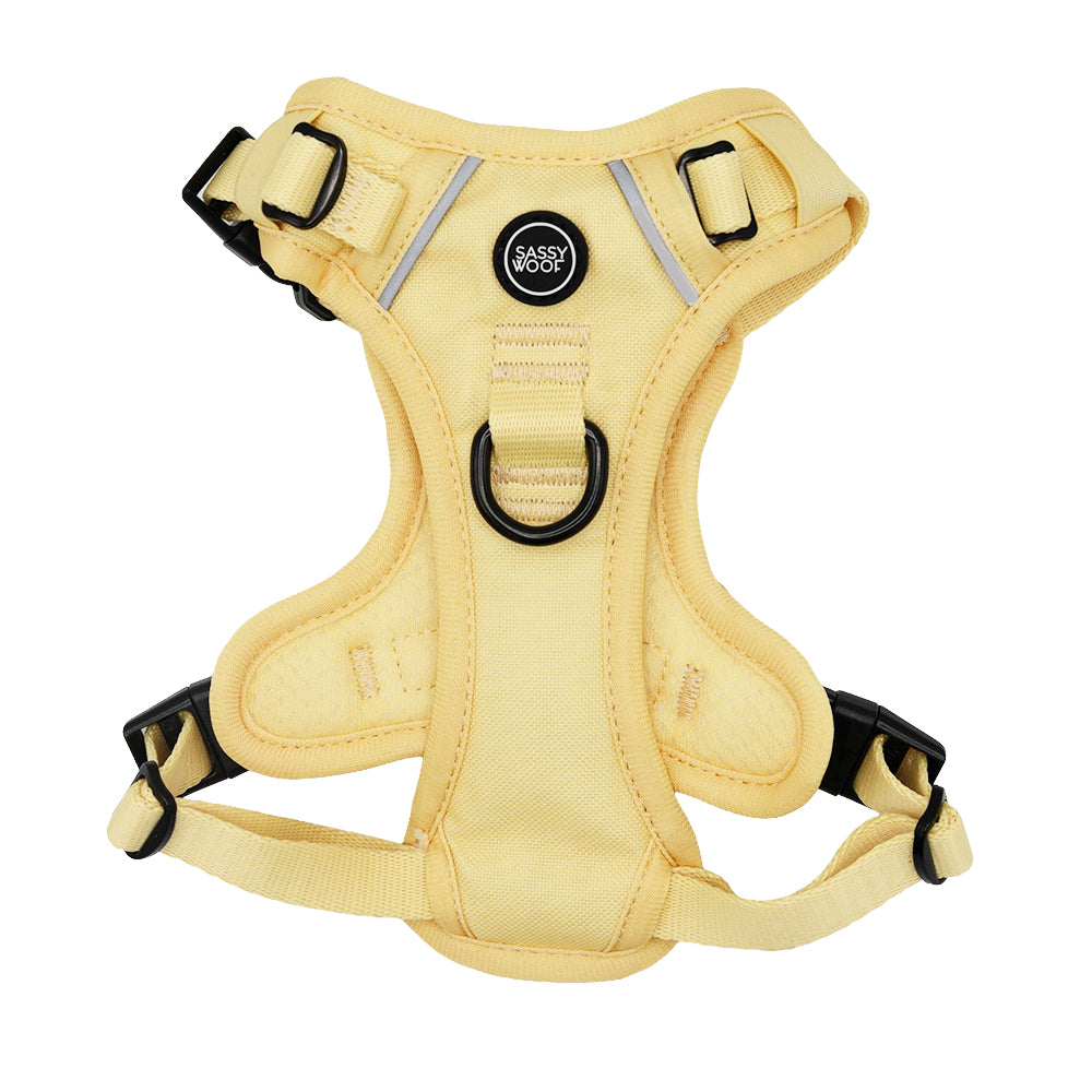 The Sassy Woof Dog Step-in Harness - Daffodil features adjustable yellow straps, black buckles, a leash D-ring, AirTag pocket for security, and a round Sassy Woof logo at the center front.