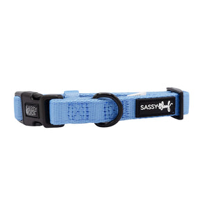 The Sassy Woof Dog Collar - Hydrangea is light blue, features a black plastic buckle, black D-ring, logo tag on the side, and is made from soft neoprene for comfort and durability.