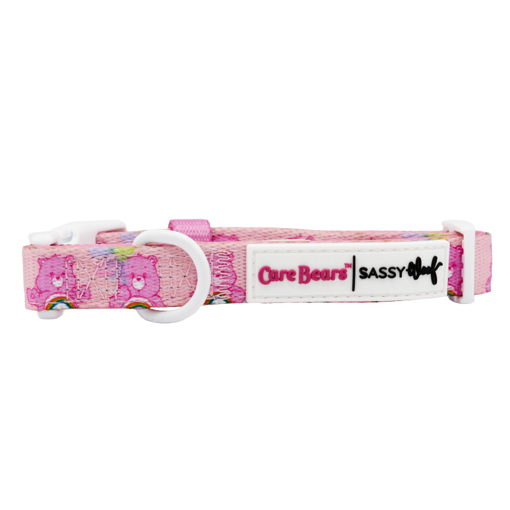 A pink Care Bears™ Cheer Bear dog collar by Sassy Woof, featuring rainbows, white plastic hardware, and a Sassy Woof x Care Bears label.