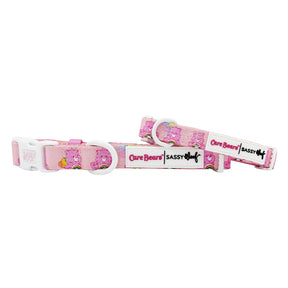 The Sassy Woof Dog Collar - Care Bears™ Cheer Bear features pink Care Bears designs, white plastic clips, and branded tags. Pair it with a matching harness for a complete Care Bears look.