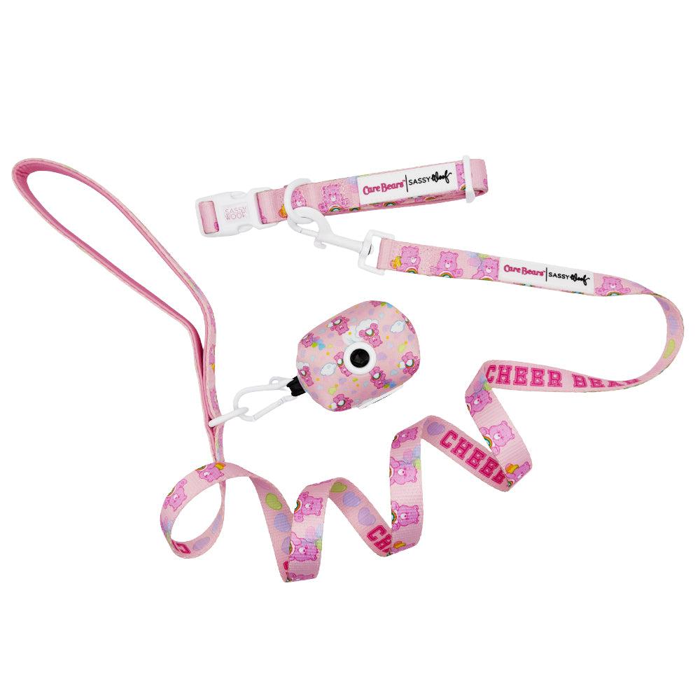 The Sassy Woof Collar Three Piece Bundle - Care Bears™ Cheer Bear includes a leash, collar, and waste bag holder with cheerful bear designs and "CHEER BEAR" lettering, plus a matching Care Bears dog harness.