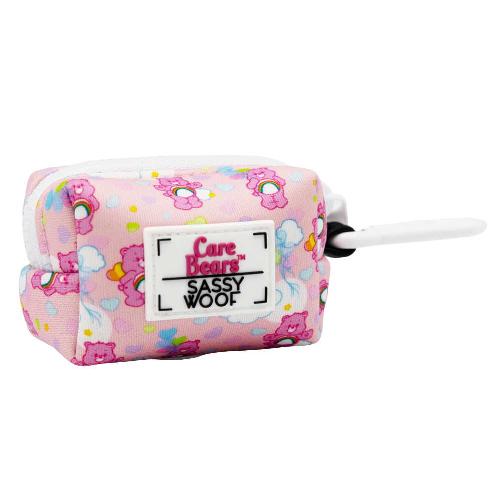 The Sassy Woof Dog Waste Bag Holder – Care Bears™ Cheer Bear is a small pink rectangular pouch with rainbow Care Bears designs, a white zipper, and black-and-white clip—perfect for pairing with your favorite Care Bears harness.