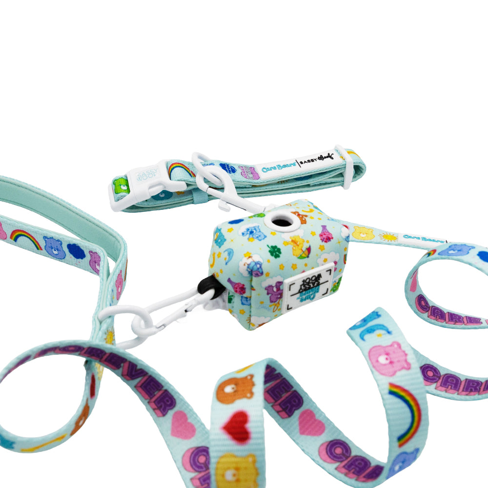 The Sassy Woof Collar Three Piece Bundle - Care Bears™ Care-a-Lot features a vibrant design with Care Bears, rainbows, and hearts on white—complete with a matching strap and lanyard—perfect for any Care Bears fan.
