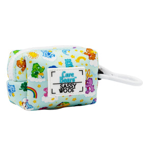 The Sassy Woof Dog Waste Bag Holder - Care Bears™ Care-a-Lot features a light blue rectangular design with bears, rainbows, stars, clouds, a front white Sassy Woof patch, and side white clip—part of the playful Care-a-Lot collection.