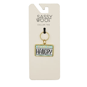 The Sassy Woof Collar Tag - Hello I'm Hangry is a license plate-style rectangular pet tag on a branded backing card, boldly declaring HELLO IM HANGRY in black—ideal for dogs with attitude!.