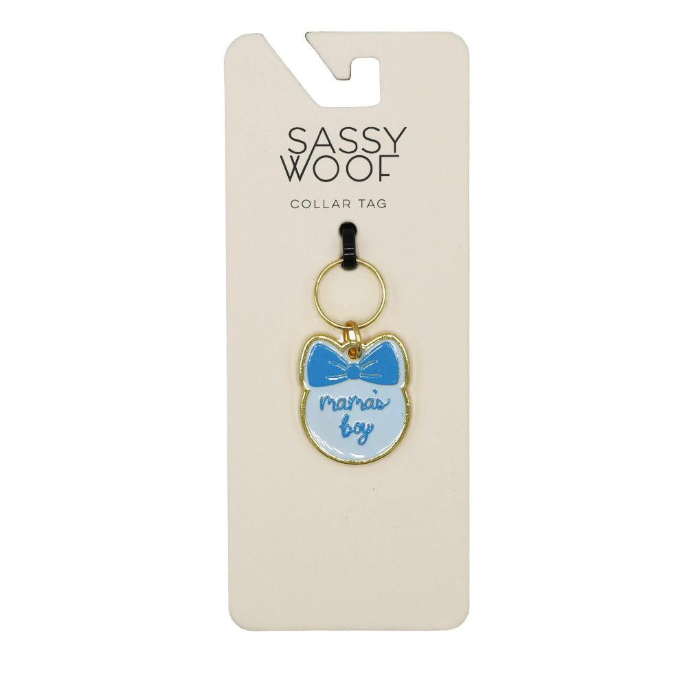 The Sassy Woof Collar Tag - Mama's Boy is a cat-shaped dog tag with a blue bow and "mamas boy" text, attached to a card featuring the Sassy Woof brand name at the top.