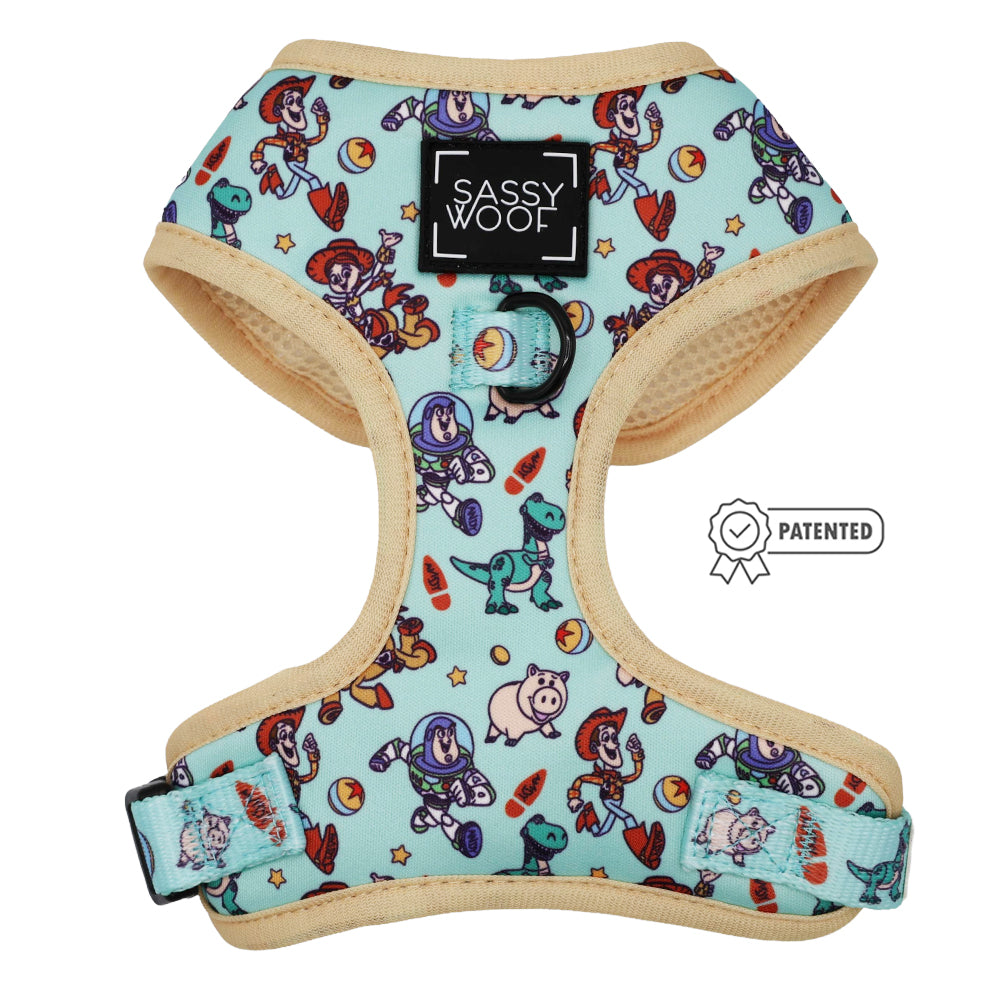 The Sassy Woof Dog Adjustable Harness - Disney and Pixar's Toy Story features a light blue design with beige trim, playful character print, black ring, Patented icon, and is eligible for the Puppy Growth Pawtection Plan.