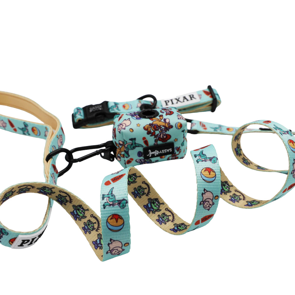 The Sassy Woof Collar Three Piece Bundle – Disney and Pixar’s Toy Story features a light blue dog collar, leash, and matching poop bag holder with Woody, Buzz Lightyear, and the Pixar logo in colorful cartoon designs.