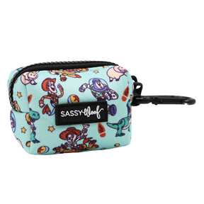 The Sassy Woof Dog Waste Bag Holder - Disney and Pixar's Toy Story features a light blue pouch with cartoon characters, stars, a black zipper, and clip. This handy pouch has a front SASSY WOOF label and is perfect for holding dog waste bags.