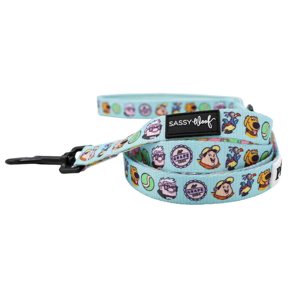 The Dog Leash - Disney and Pixar's Up by Sassy Woof features playful cartoon dog faces, tennis balls, grape soda motifs, a black metal clasp, and a Sassy Woof label—perfect for pairing with an adventure dog harness on fun outings.