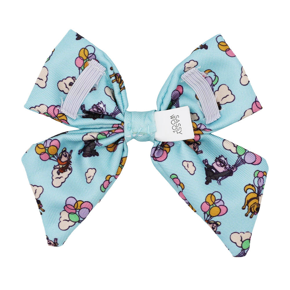 The Sassy Woof Dog Sailor Bow – Disney and Pixar's Up features colorful balloons, clouds, and dogs with balloons, plus a white logo label in the center and two lilac grosgrain ribbon accents. Perfect for fans of Disney Up dog accessories!.